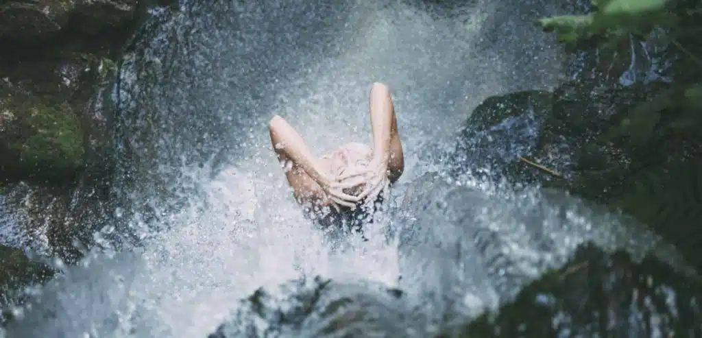 Femme prenant une douche naturelle dans une cascade